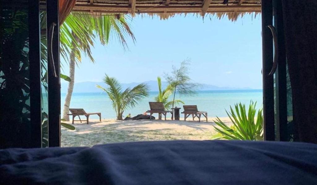 a view of a beach with benches and the ocean at Papillon Bungalows in Baan Tai