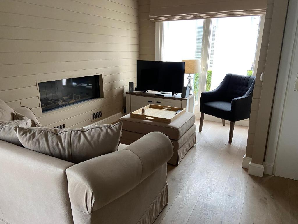 un soggiorno con divano, TV e sedia di Chalet Eau Vive a Maaseik