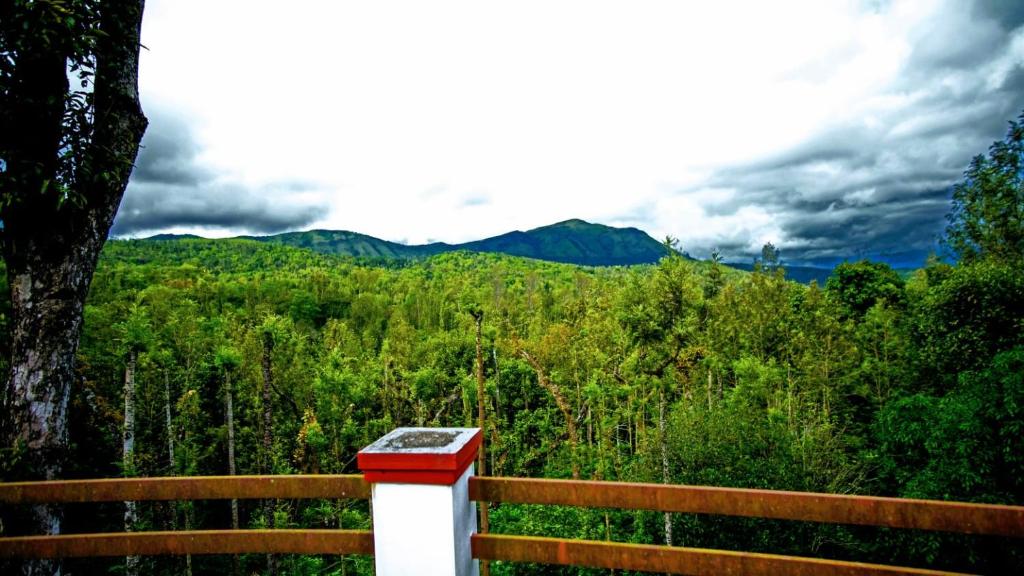 a red and white box on a wooden fence with a mountain at Memories of Malnad in Chikmagalūr