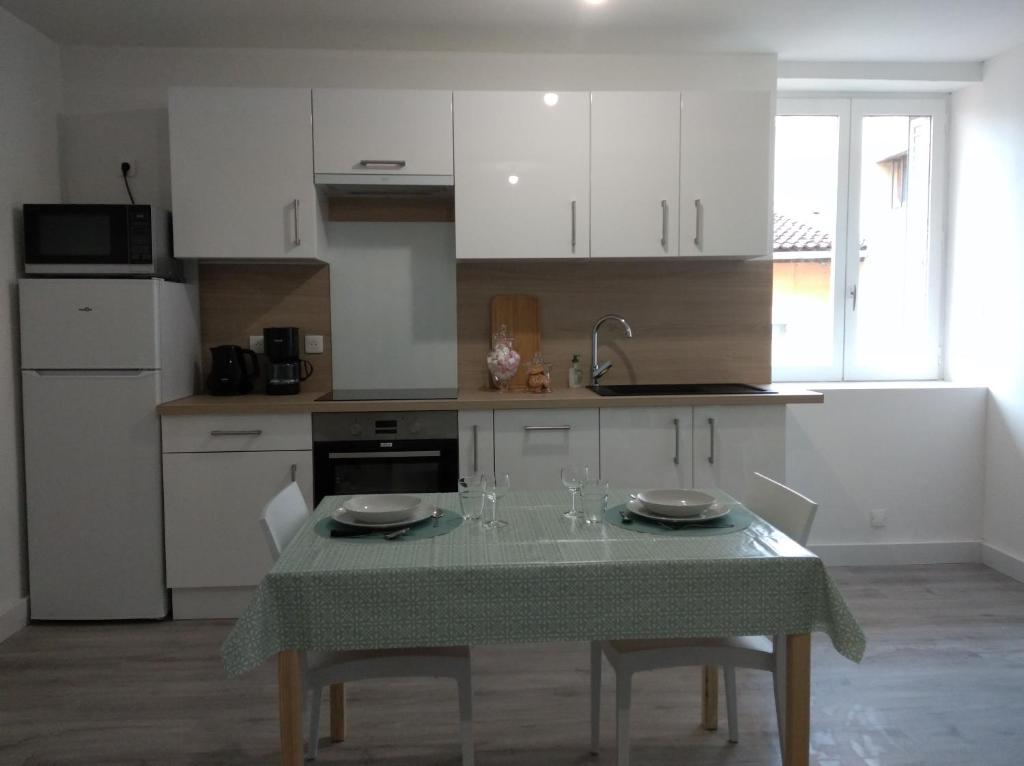 a kitchen with a table with a green tablecloth on it at T2 - 2 à 3 personnes - draps et serviettes en option in Lorette