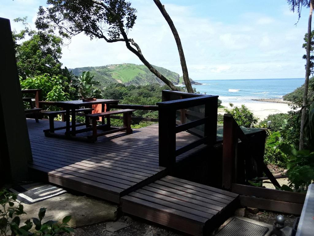 a wooden deck with benches and a view of the ocean at Delicious Monster Accommodation in Port St. Johns