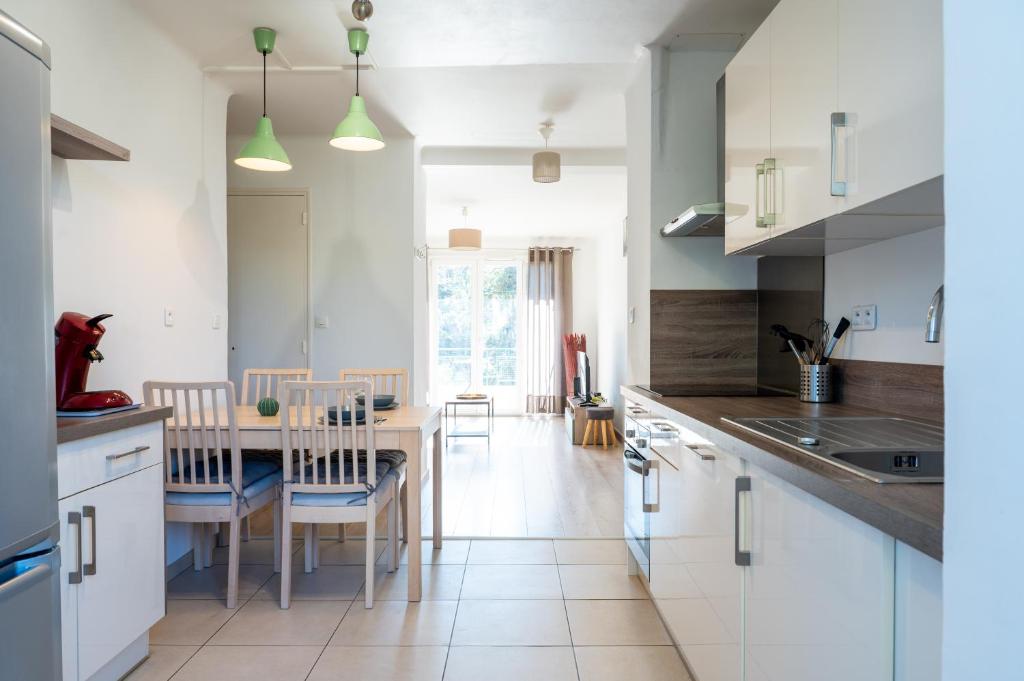 a kitchen with white cabinets and a table and chairs at Résidence La Source in Toulon
