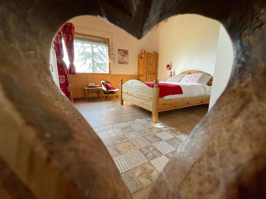 ein Schlafzimmer mit einem Bett durch eine herzförmige Öffnung in der Unterkunft Chalet de Rozan in La Tronche