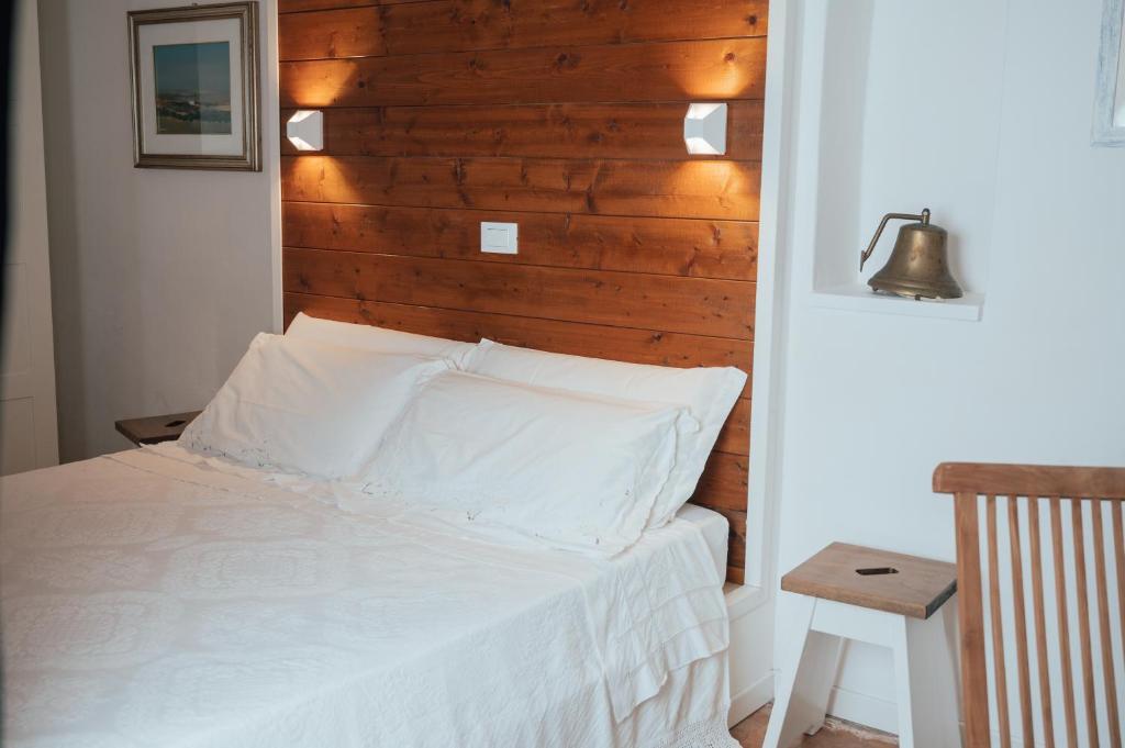 1 dormitorio con cama blanca y cabecero de madera en La Quercia In Giardino, en Ducato di Fabriago