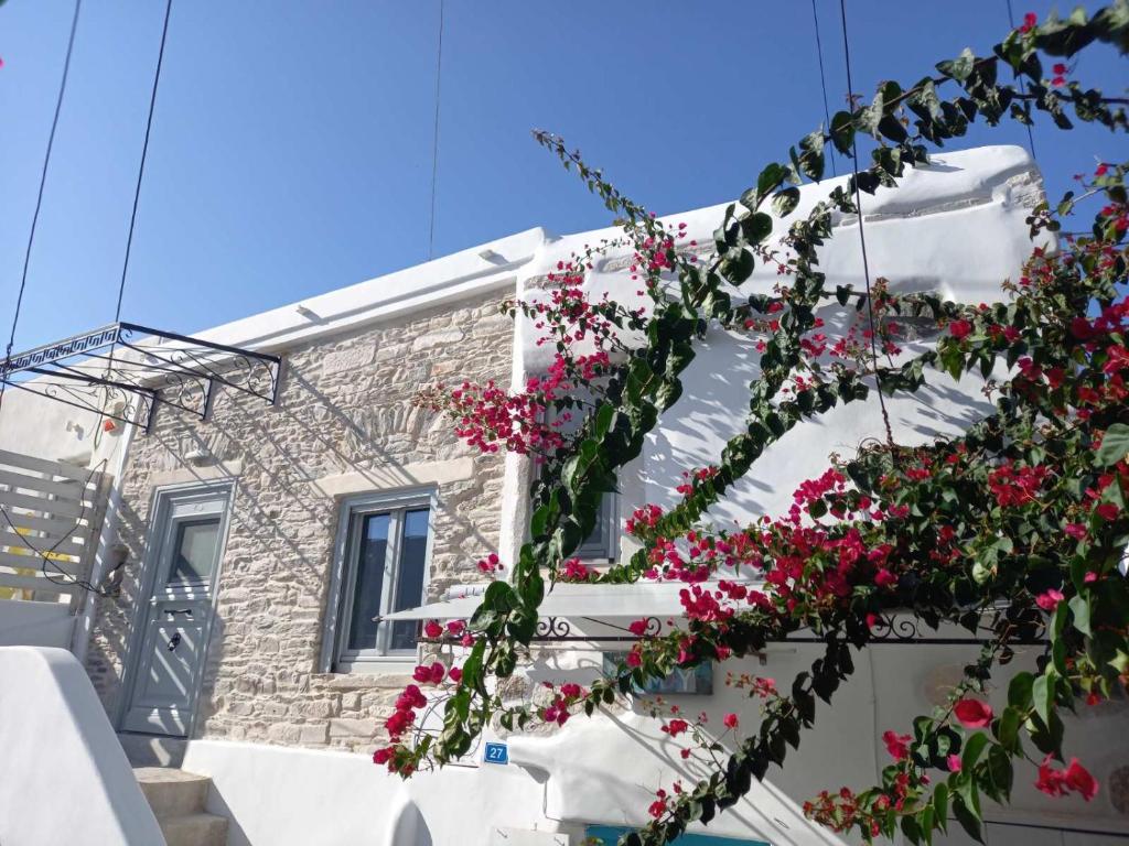un bâtiment blanc avec des fleurs roses sur lui dans l'établissement Tristrato, à Parikia