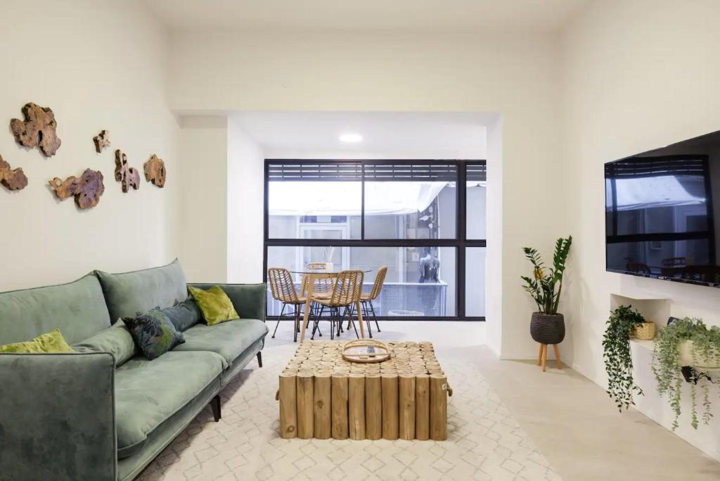 a living room with a green couch and a table at RENOVATED LARGE 3RM APARTMENT 5 MIN FROM THE BEACH in Tel Aviv