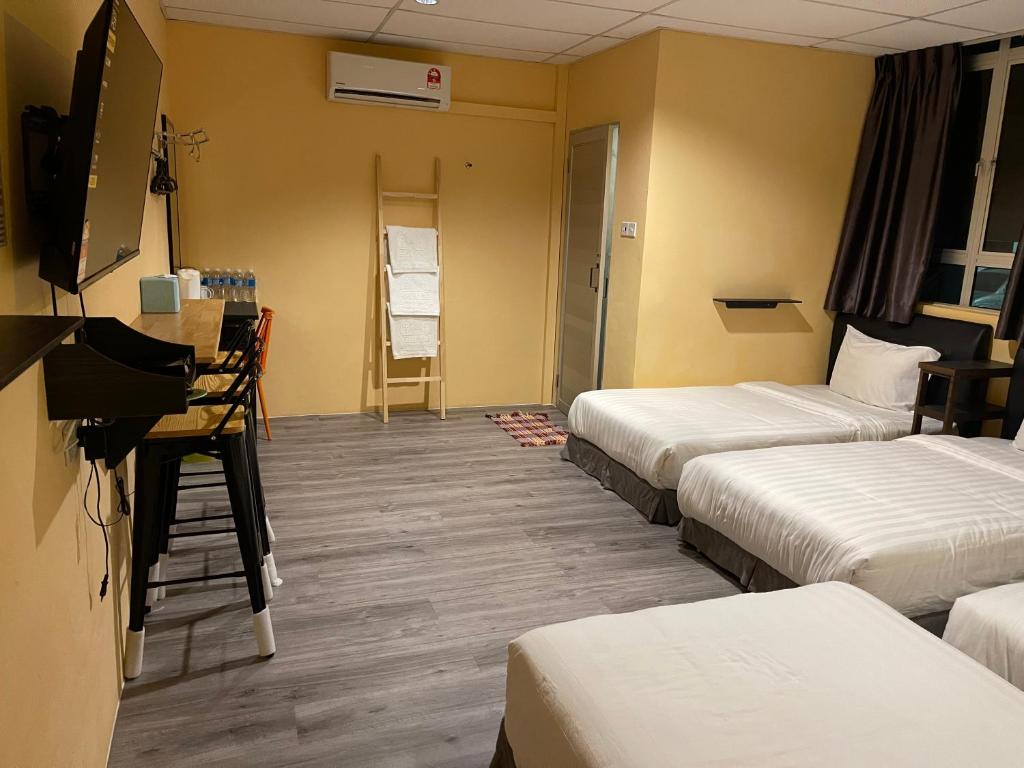 a hotel room with three beds and a television at Loft Pals Urbanstay Lodge, Kapit in Kapit