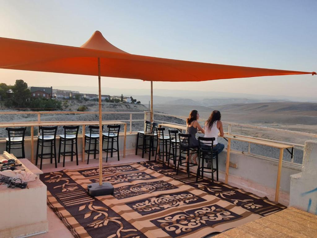 two women sitting at a table under an umbrella at רוג'ום גסטהאוס Rujum in Arad