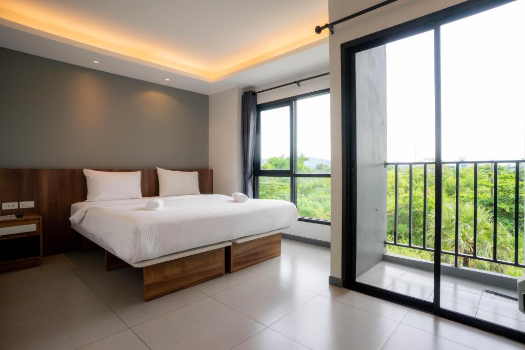 a bedroom with a large bed and large windows at The Zleep Chonburi in Chon Buri