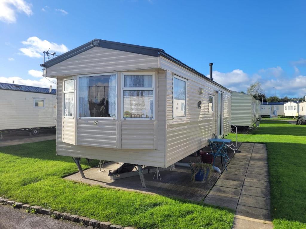 a white tiny house sitting in the grass at 54 Family Caravan at Marine Holiday Park, sleeps 4 in Rhyl