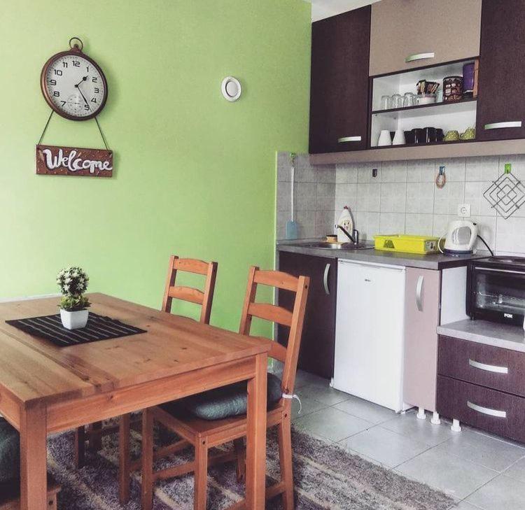 een keuken met een houten tafel en een klok aan de muur bij Vila Vedrana Apartman Nedeljkovic in Brzeće