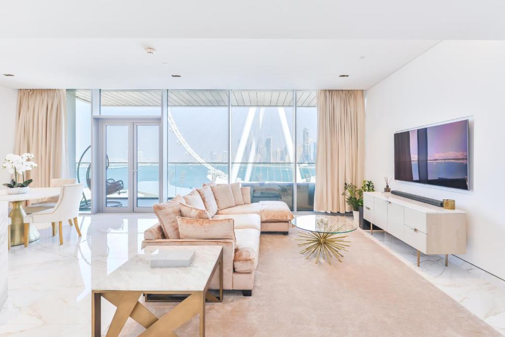 ein Wohnzimmer mit einem Sofa und einem TV in der Unterkunft Luxury 2 BR Beachfront Apt w stunning sea view in Dubai