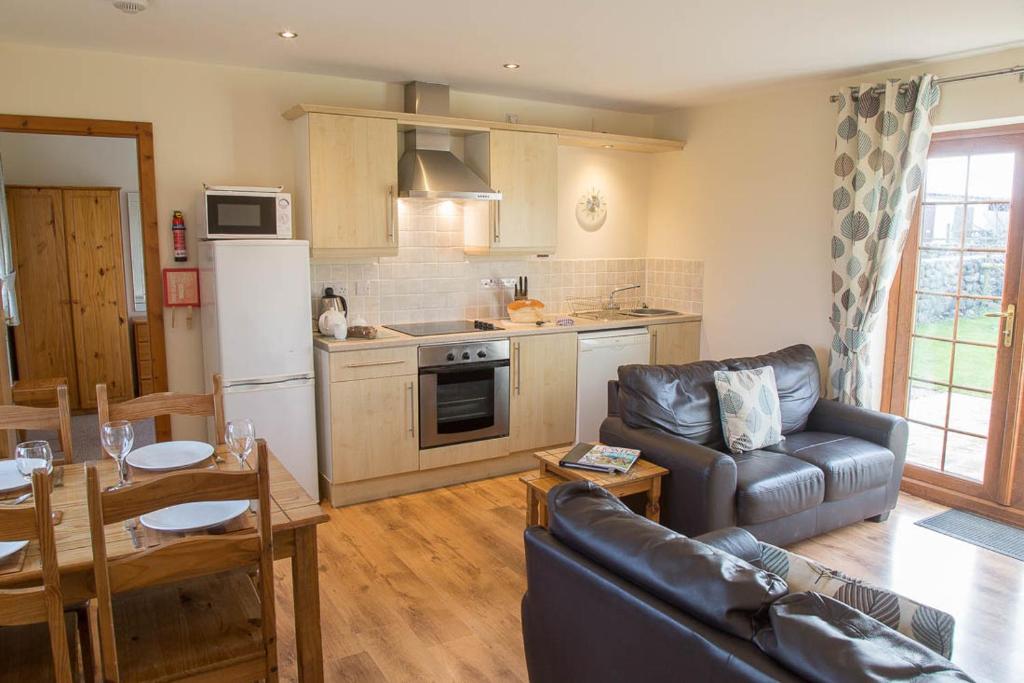 a living room with a couch and a kitchen at Carnedd Cottage in Dwyran