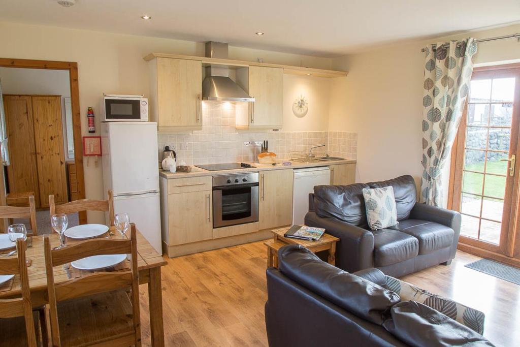 Una sala de estar con un sofá y una cocina. en Carnedd Cottage, en Dwyran