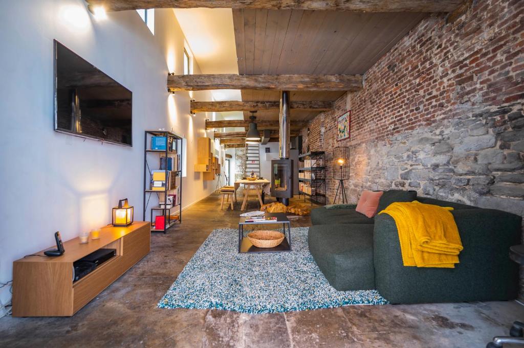 a living room with a green couch and a brick wall at L'atelier de Liège: Tranquillité & Effervescence in Liège