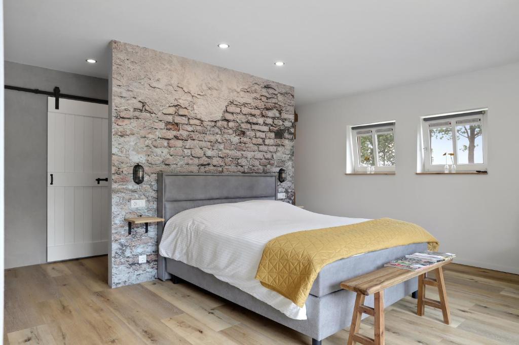 a bedroom with a brick wall and a bed at Vakantiehuis Bij Vermeer in Een