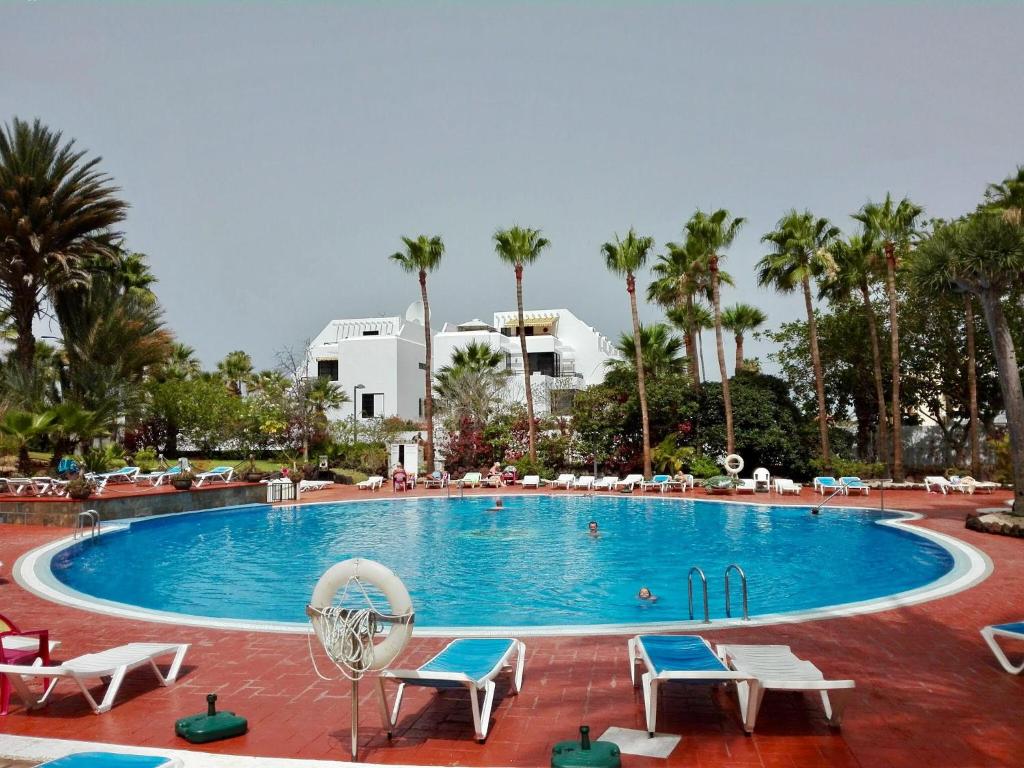 a large swimming pool with chairs and palm trees at Аpartment 1 bedroom center of Las Americas El Dorado in Playa de las Americas