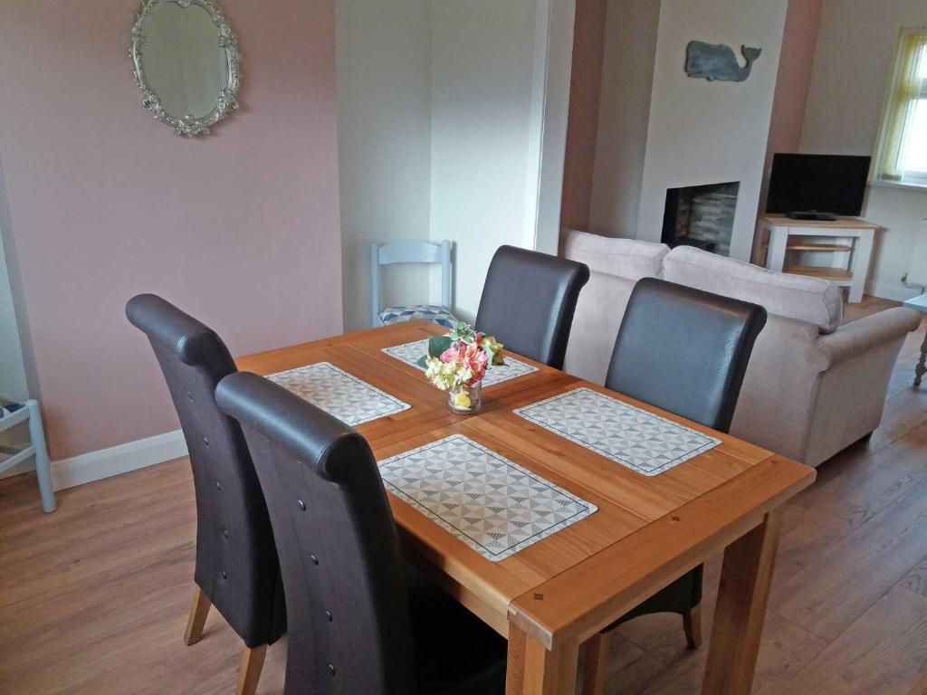 a wooden dining room table with chairs and a couch at Lough Conn Holiday Home in Crossmolina