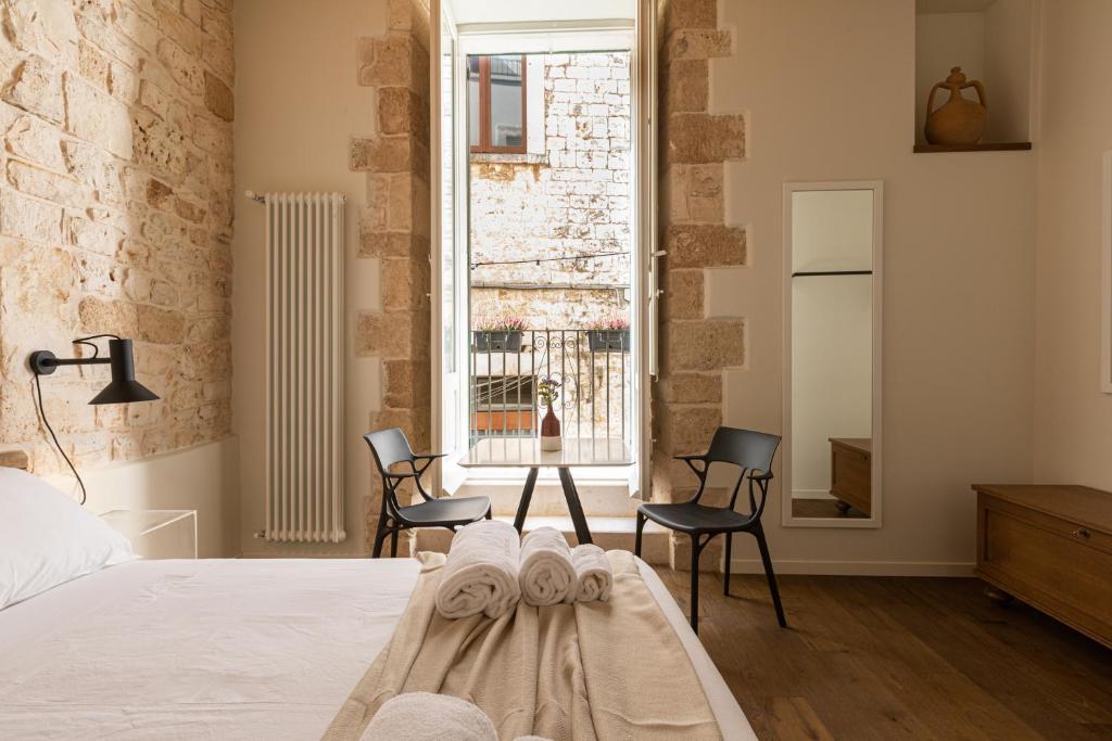 a bedroom with a bed with two chairs and a window at Casa Badia Bed & Breakfast in Conversano