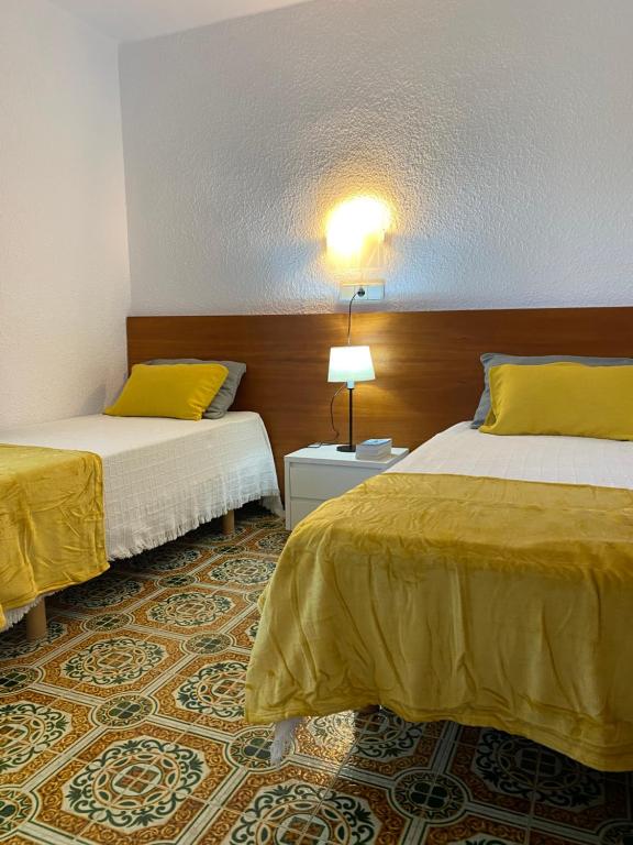 Habitación de hotel con 2 camas con sábanas amarillas en VILLA CATALUNYA, en Cambrils