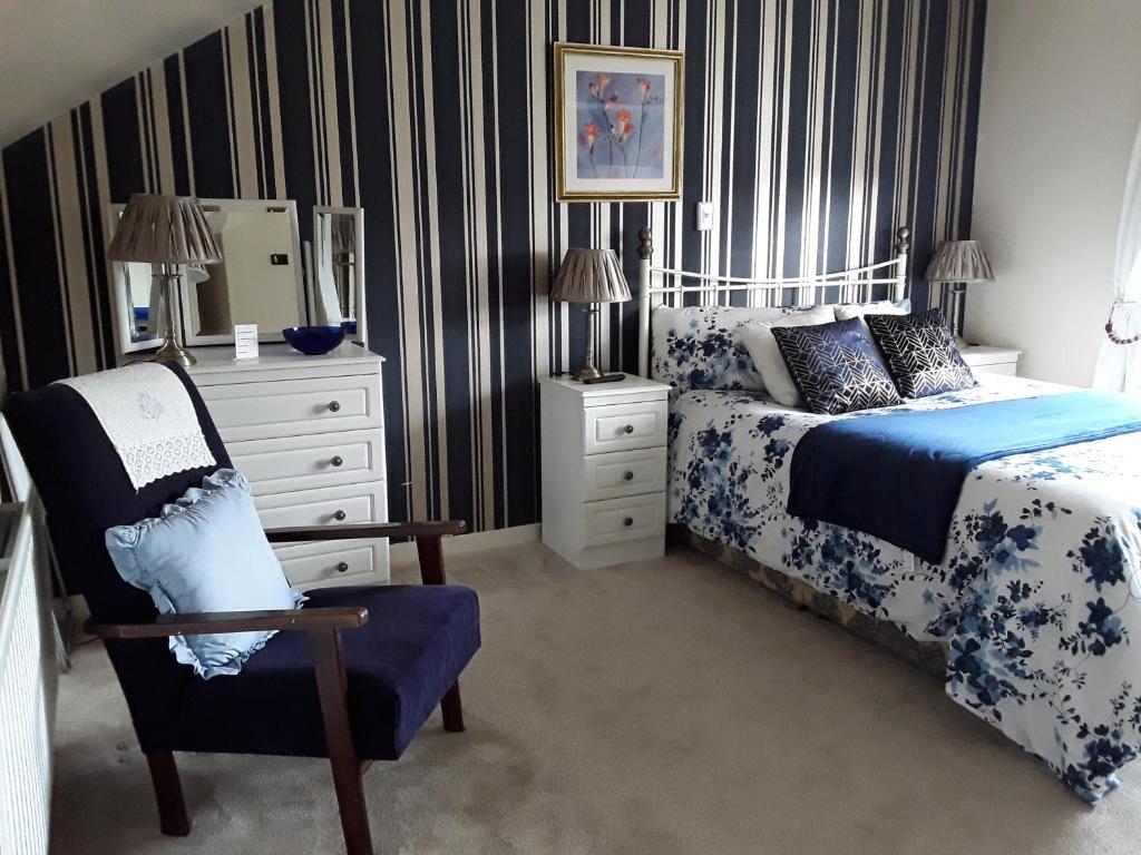 Grangeview House B&B في Mullinderg: غرفة نوم بسرير وكرسي وخزانة