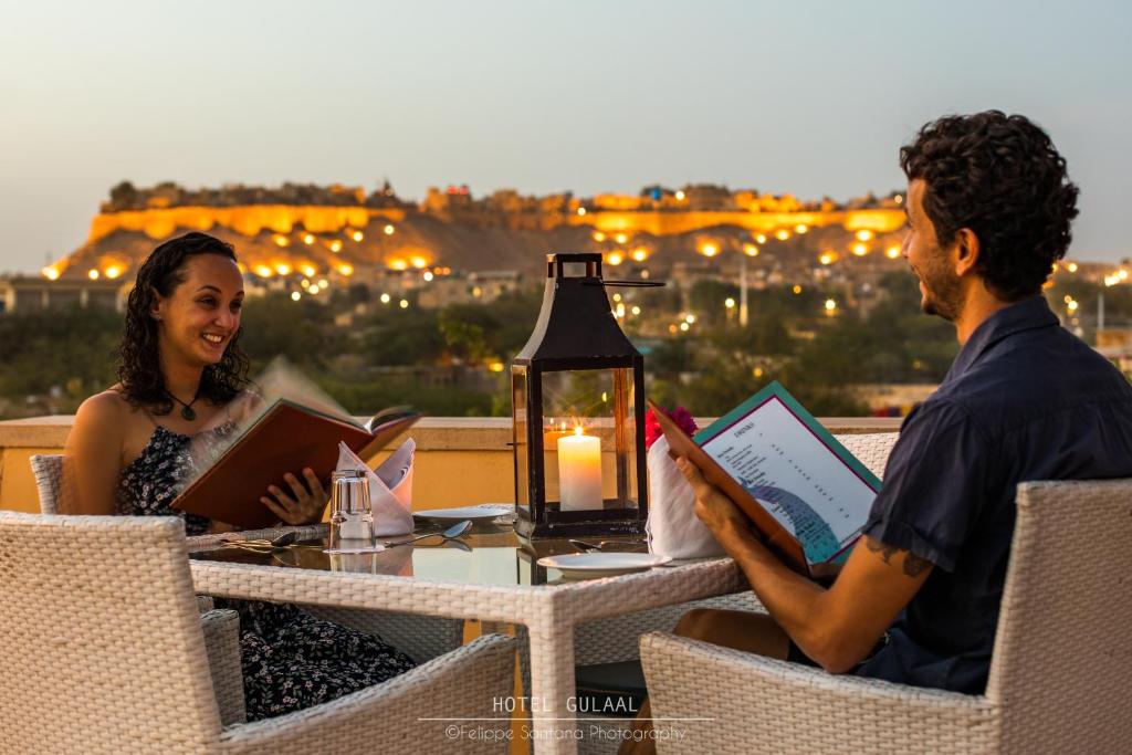 Un uomo e una donna seduti a un tavolo con dei libri di The Gulaal a Jaisalmer