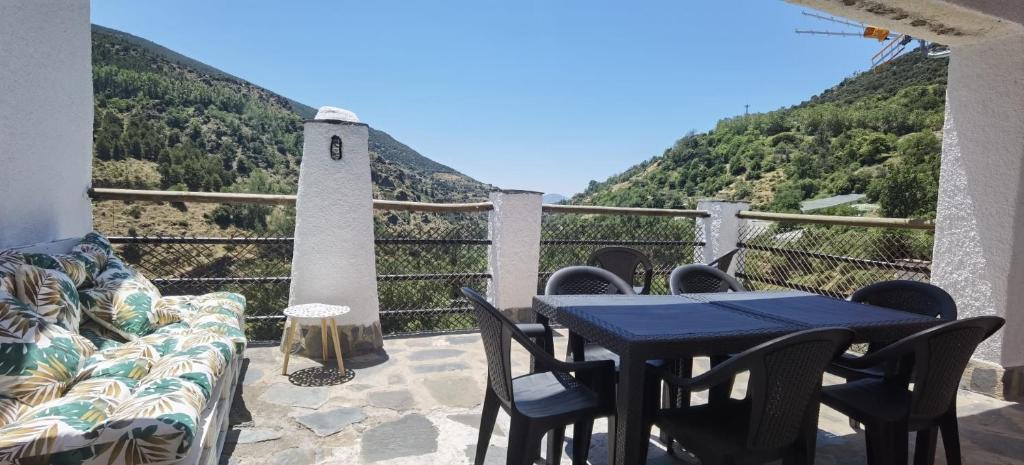 eine Terrasse mit einem Tisch und Stühlen sowie Bergblick in der Unterkunft El Capricho de Trevélez in Trevélez