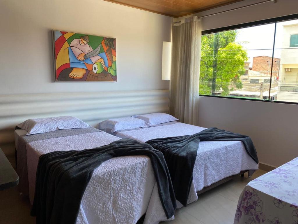 two beds in a room with a window at Flat no Caribe in Maragogi