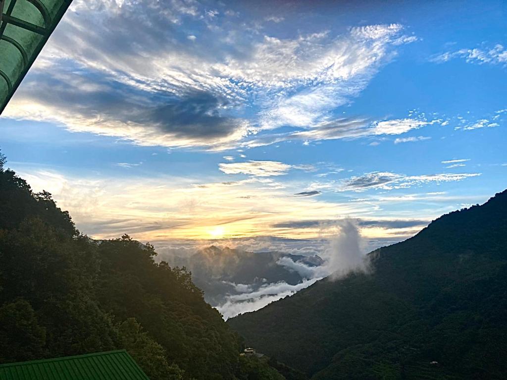 a view of a valley in the mountains with the sun setting at Junlin Holiday Farm in Hualing