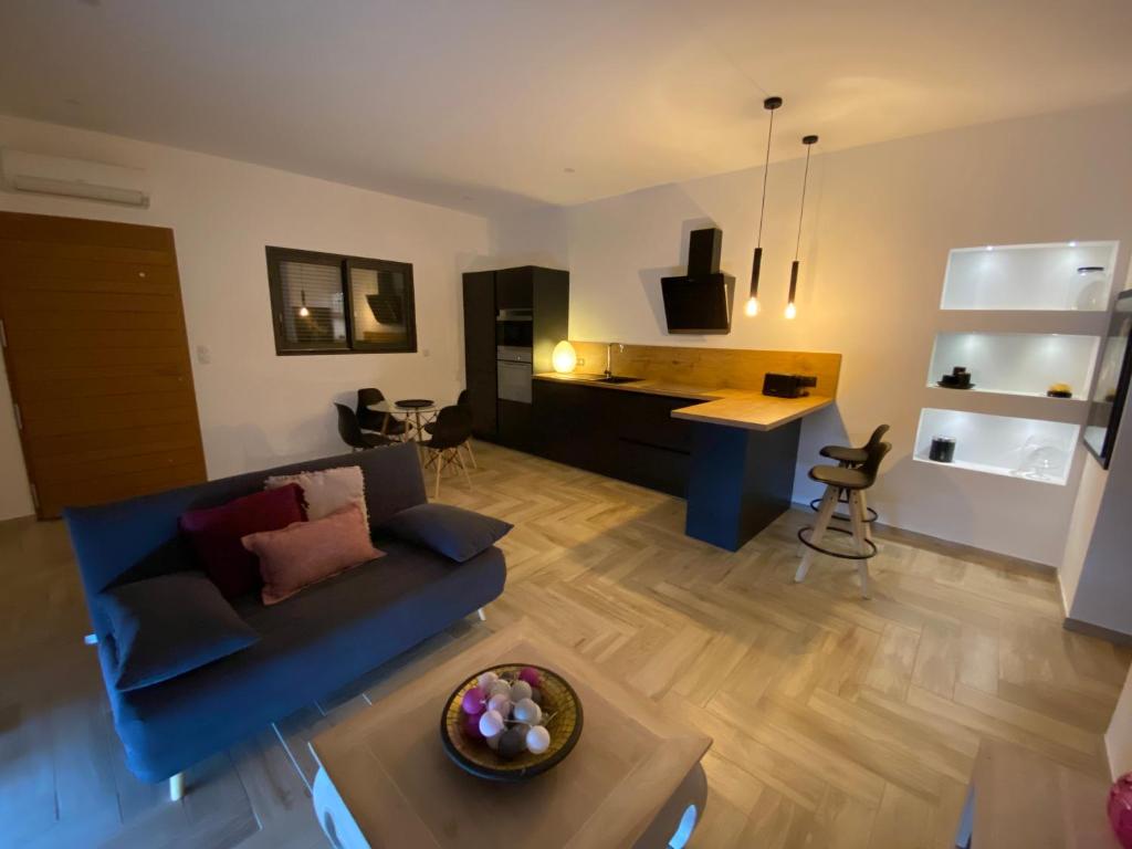 a living room with a blue couch and a kitchen at Chjama di mare in Santa-Maria-di-Lota