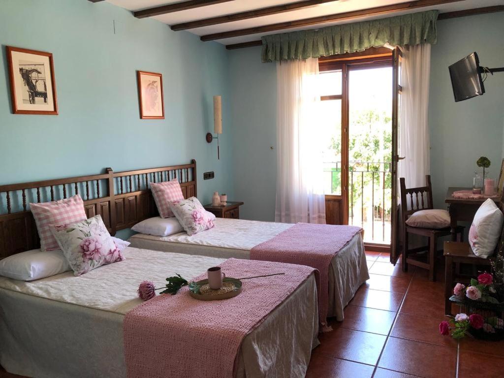 a hotel room with two beds and a window at Hotel Rural El Vedal in Muelas del Pan