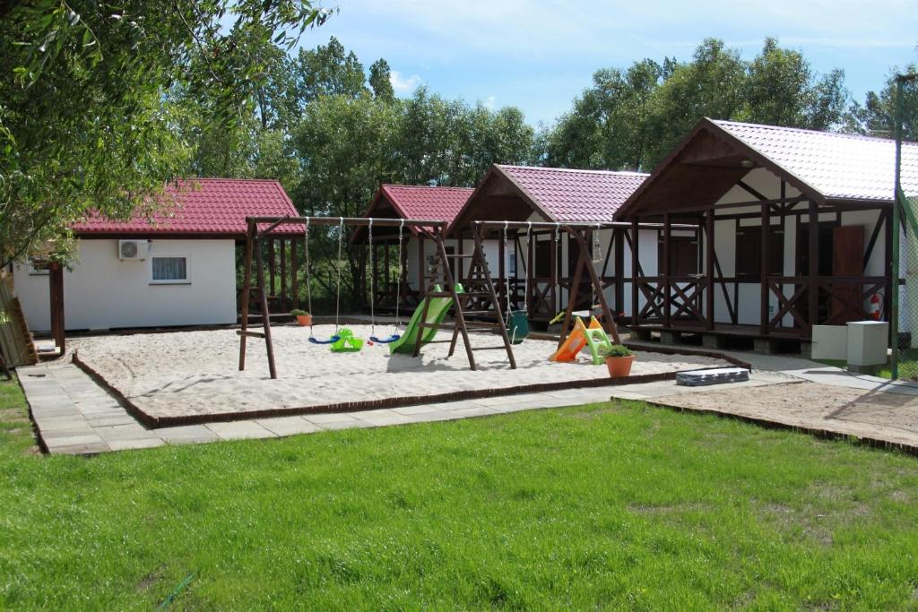 a playground in a yard with two houses at Łeba Domki z Klimatyzacją in Łeba