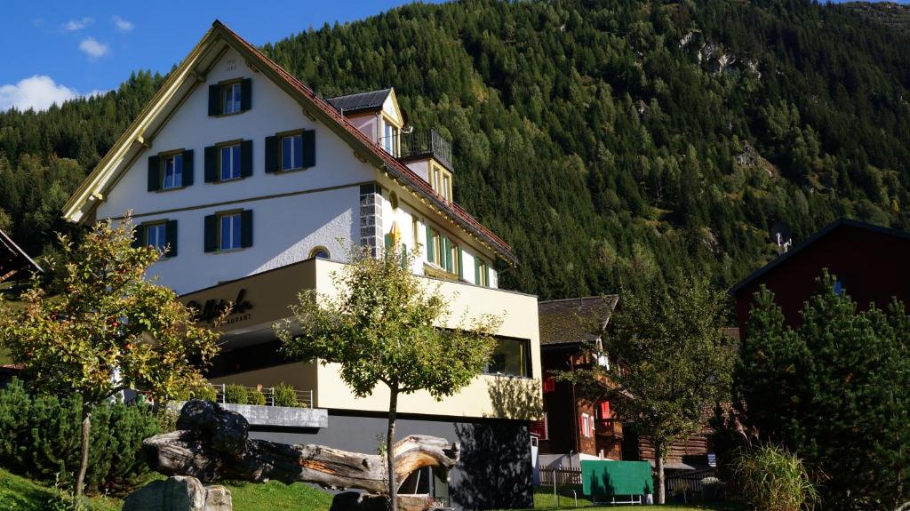 Hotel Vallatscha في Curaglia: بيت ابيض كبير وجبل في الخلف