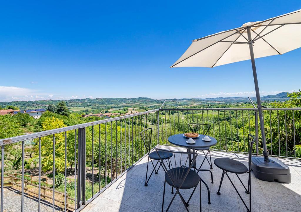 - un balcon avec une table, des chaises et un parasol dans l'établissement Casa di nonna Ines 1 - Hideaway in Monferrato con Vista sulle Colline, Solarium e Piscina, à Gabiano