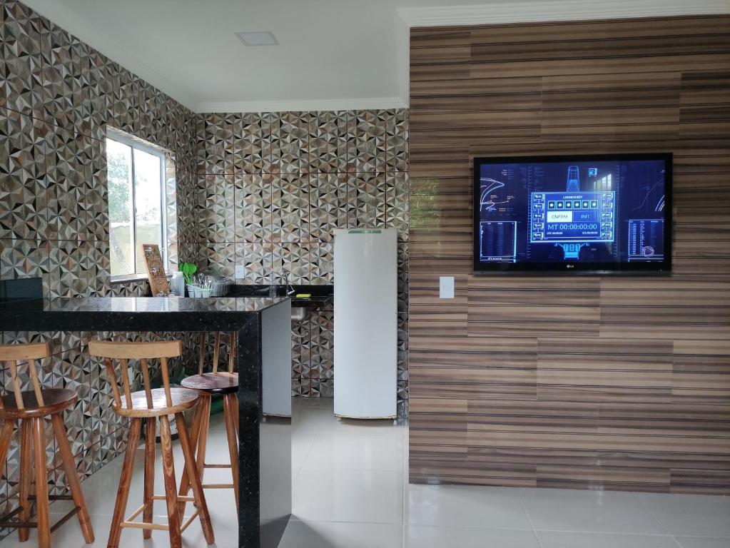 a kitchen with a refrigerator and a television on a wall at Pedacinho do céu in Cabo Frio