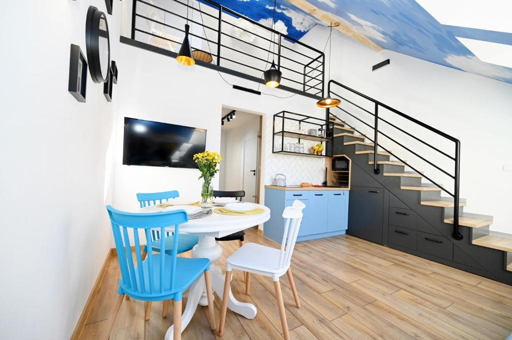 a kitchen and dining room with a white table and blue chairs at Szczyrk Apartament Niebo - sauna 6 osób in Szczyrk