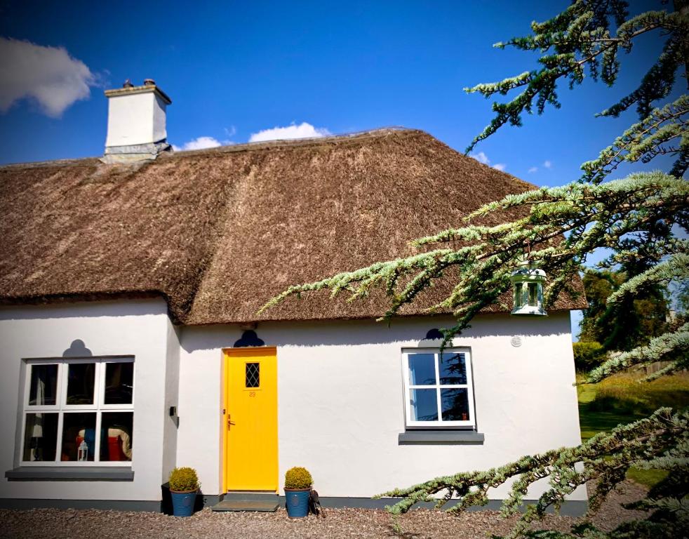 un cottage au toit de chaume avec une porte jaune dans l'établissement Old Killarney, à Killarney