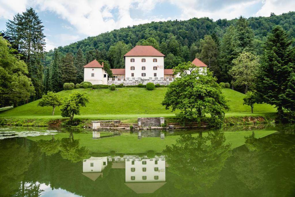 ein großes Haus auf einem Hügel neben einem See in der Unterkunft Grad Strmol in Cerklje na Gorenjskem