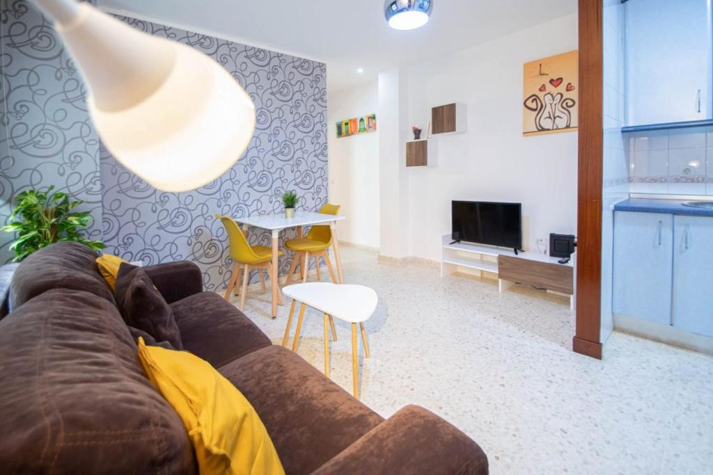 a living room with a couch and a table and a kitchen at Esencia de Cádiz Entre la Viña y el mercado in Cádiz