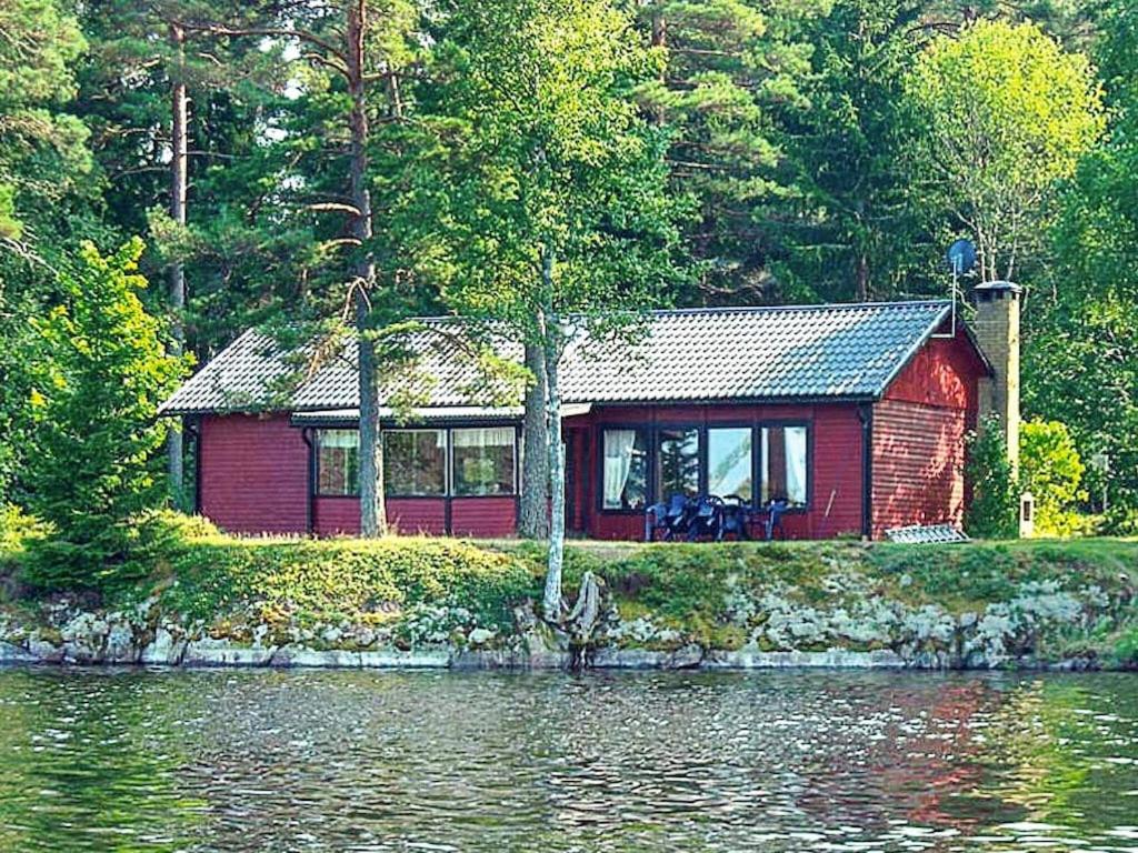 una cabina roja a orillas de un cuerpo de agua en 6 person holiday home in Vena, en Vena