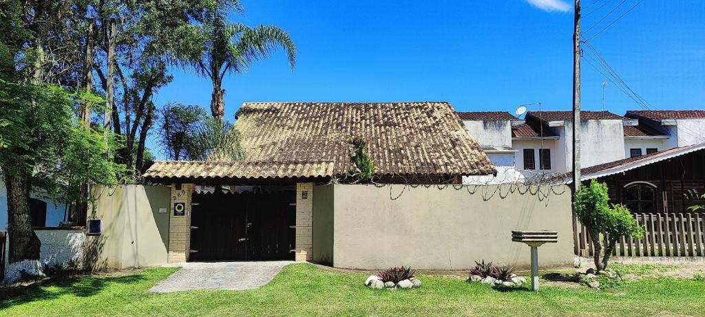 ein Haus mit einem Strohdach im Hof in der Unterkunft Linda casa c/ piscina e conforto próximo do Mar in Itapoa