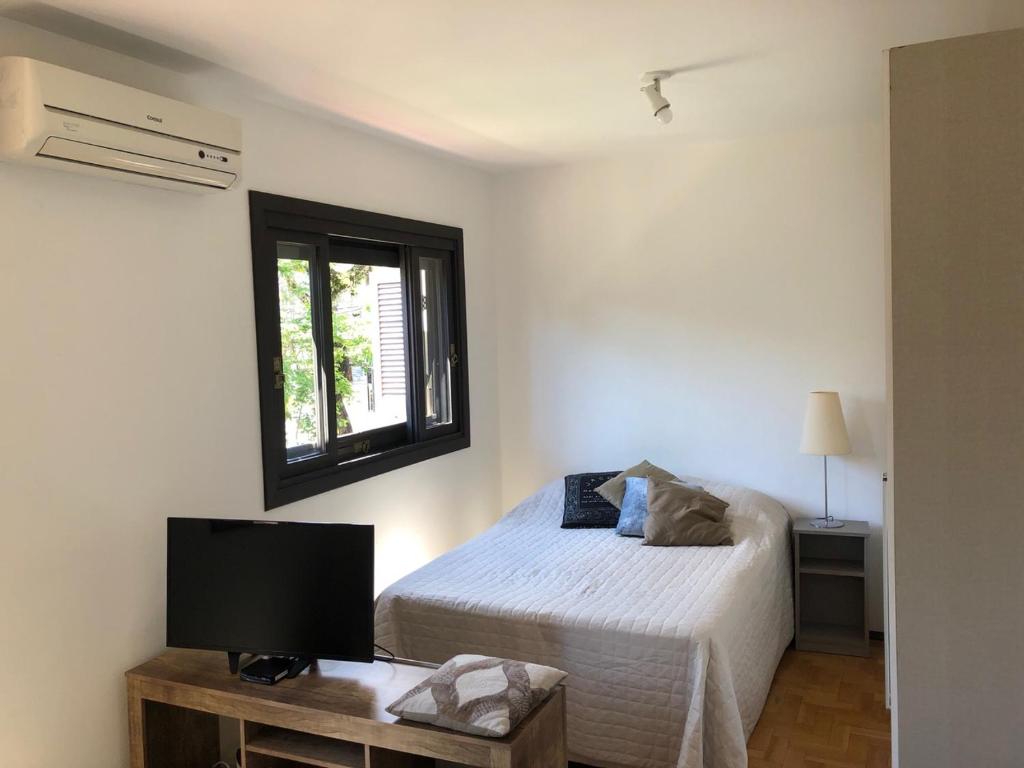 a bedroom with a bed and a tv and a window at POA Auxiliadora melhor opção in Porto Alegre