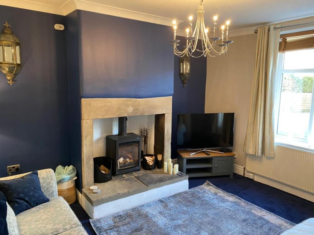 a living room with a fireplace and a tv at Honeybee Cottage, with a log fire & a hot tub. in Bradford