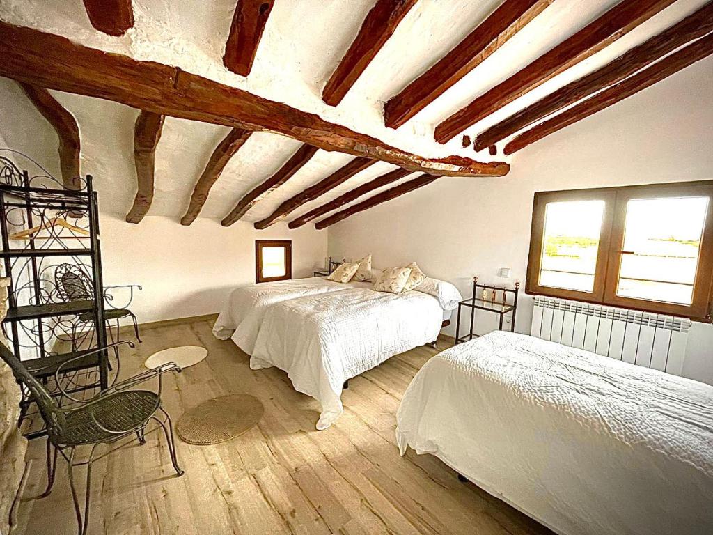 1 dormitorio con 2 camas en una habitación con techos de madera en El Refugio del Cierzo, en Vera de Moncayo