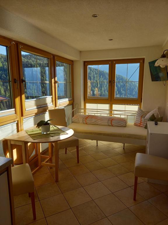 a room with a couch and a table and windows at Haus Panorama in Umhausen