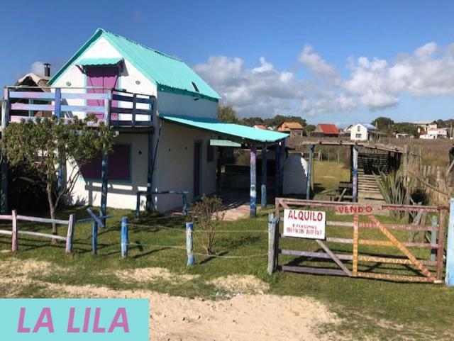 una pequeña casa con un cartel delante en La Lila, en Barra de Valizas