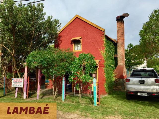 una casa roja con un coche aparcado delante de ella en Lambae, en Barra de Valizas