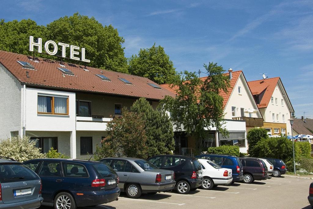 une rangée de voitures garées dans un parking en face d'un hôtel dans l'établissement Landhotel Gasthof am Berg, à Dornstadt