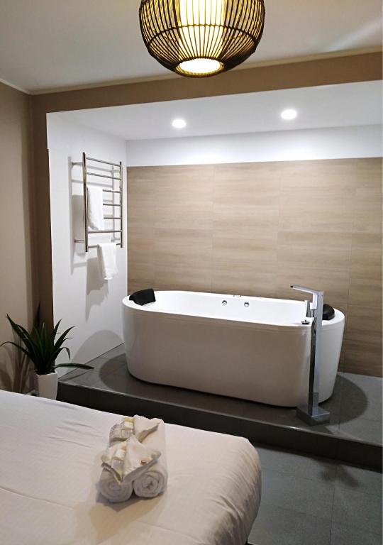 a bathroom with a tub and a bed with slippers at Snow Gum Apartment 1 in Baw Baw Village