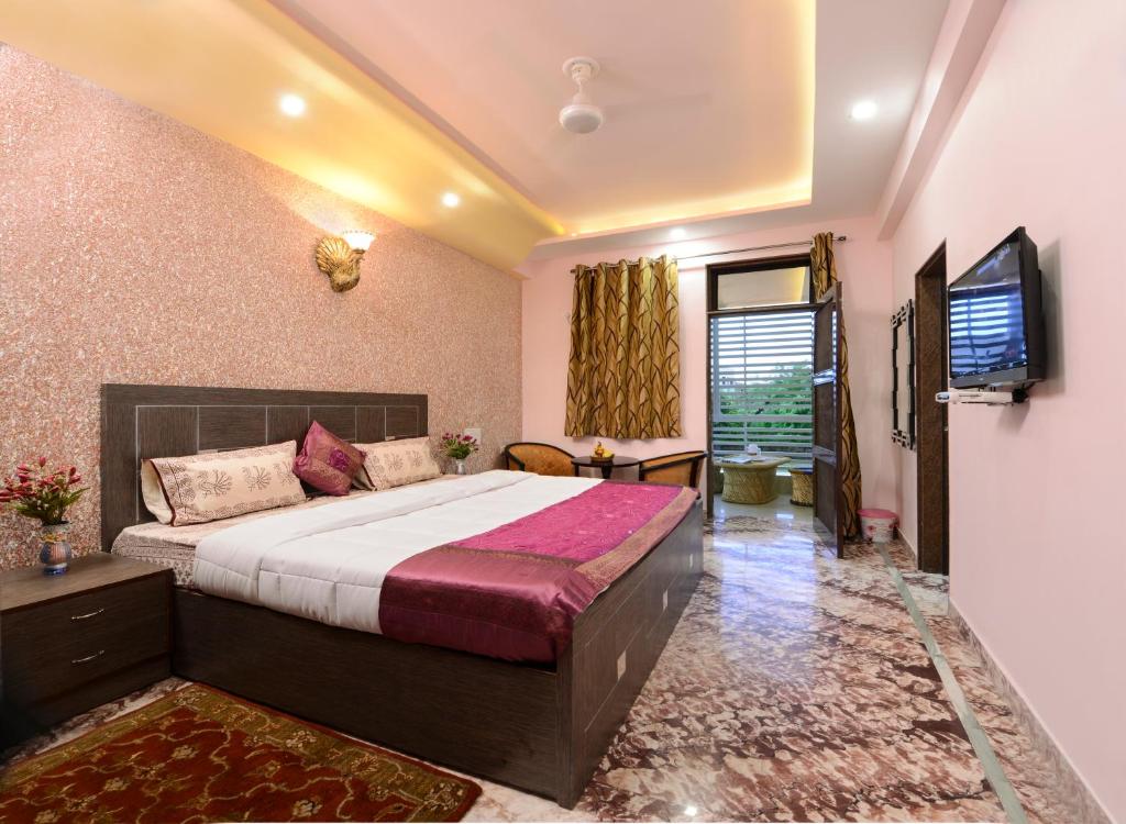 um quarto com uma cama grande e uma televisão em Rainbow Home Stay em Agra